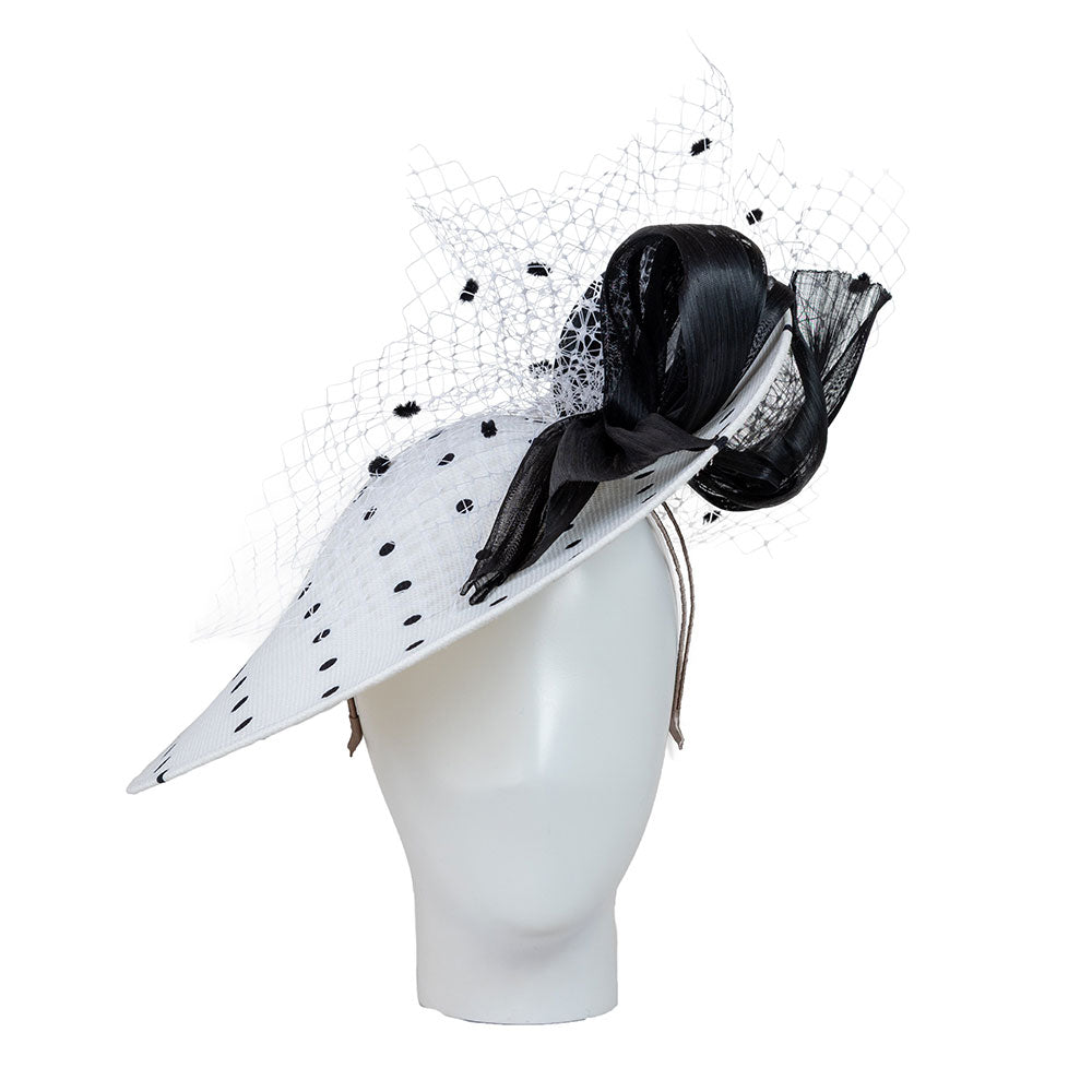 Hat for the Ascot Royal enclosure, white hat with black polka dots and decorative elements on a beige background